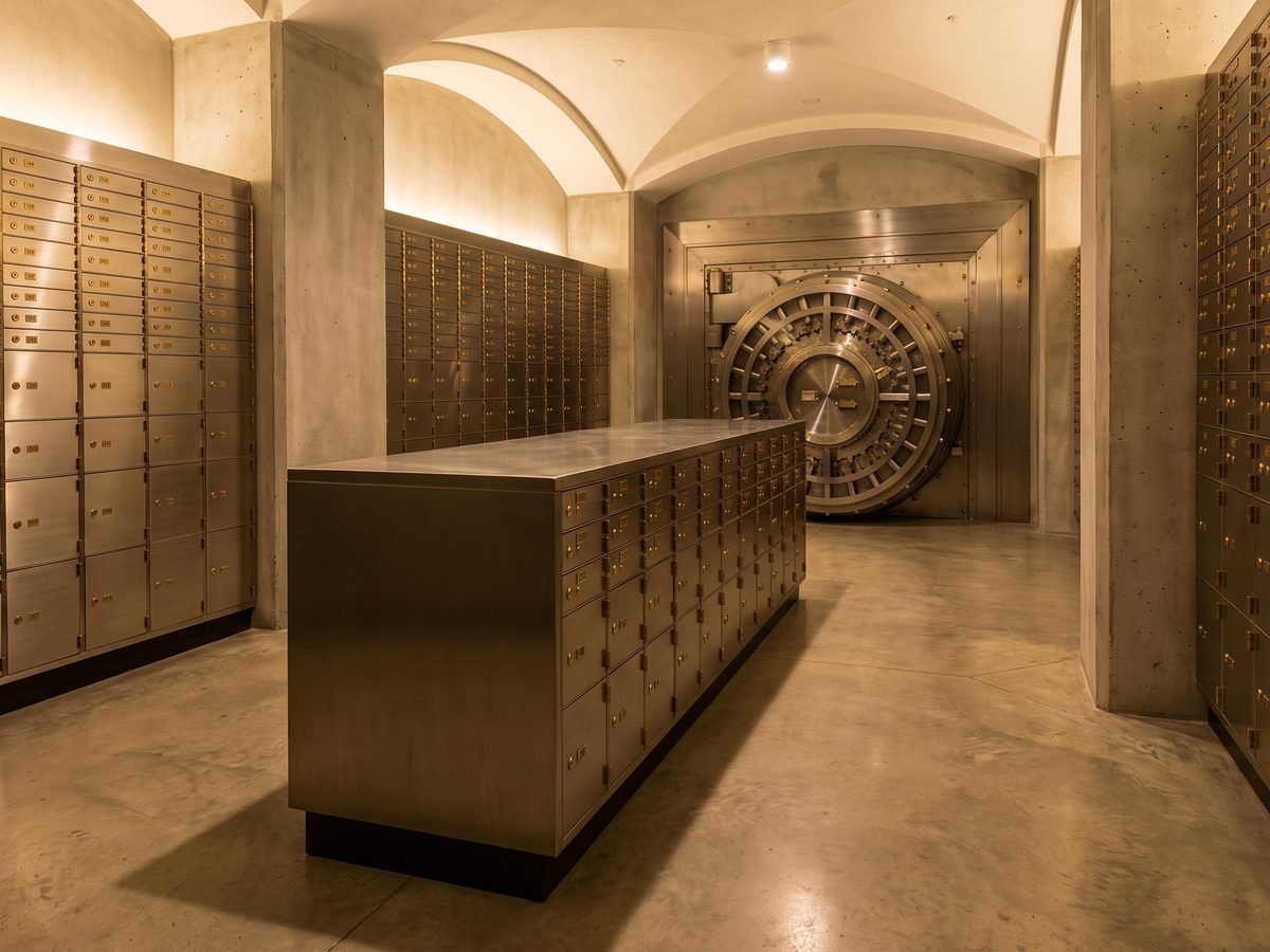 A bank vault chamber lined with brass safe-deposit boxes and a circular vault door, representing ChainForge's custody module